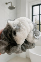 LatherDrop foam on loofah over white bathroom setting. 